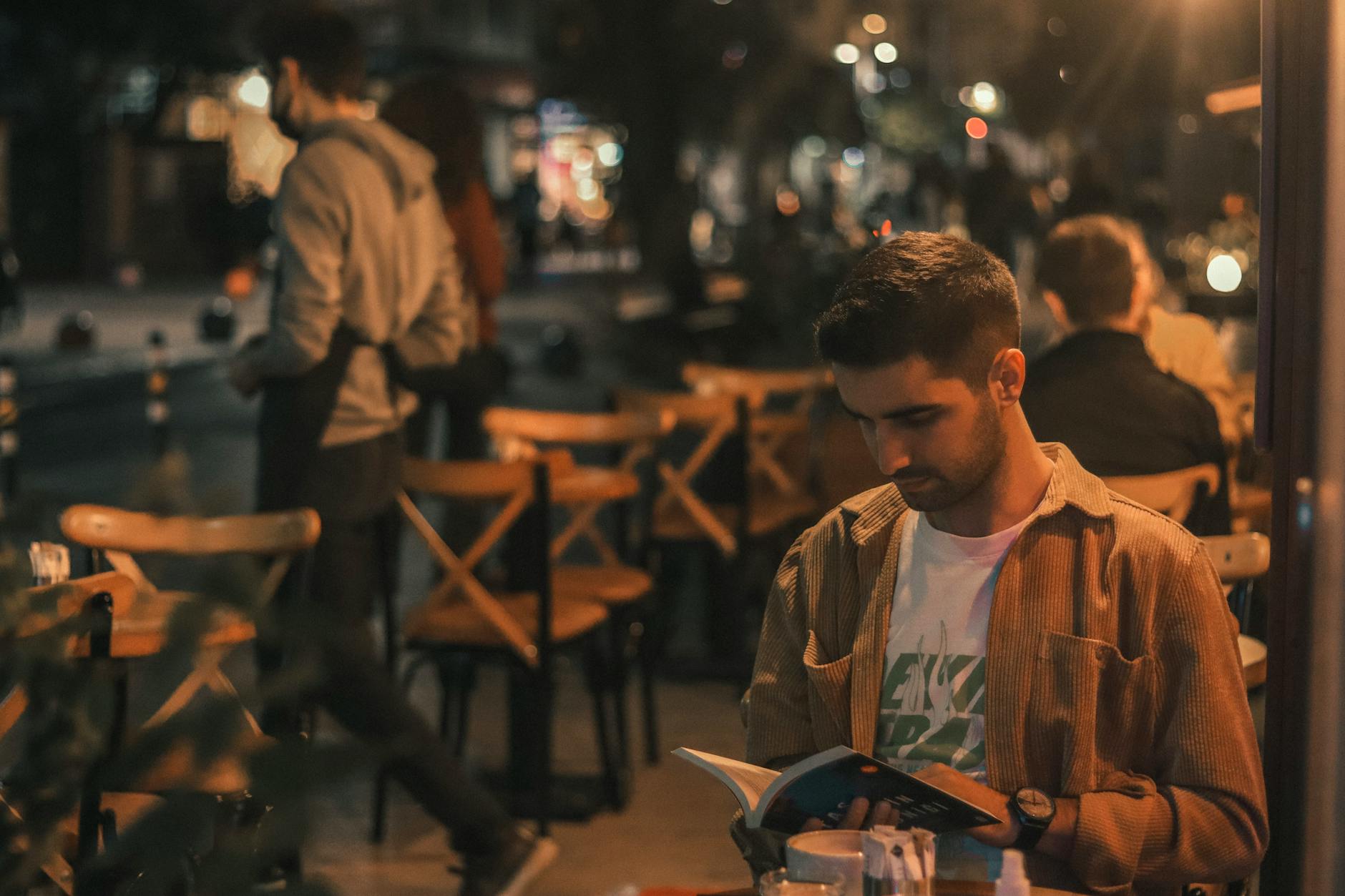 Tek kişilik akşam yemeği masasında kitap ve kadeh